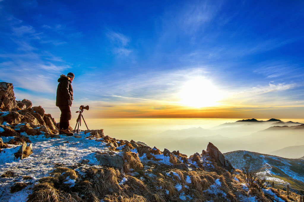 professional photographer takes photos with camera tripod rocky peak sunset 1