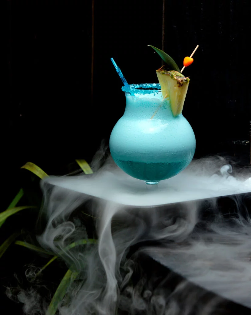 ถ่ายยังไงให้ดูเย็น เคล็ดลับการสร้างภาพถ่ายเครื่องดื่มด้วย PMI Smoke Ninja 3 glass foamy blue cocktail garnished with pineapple slice 1